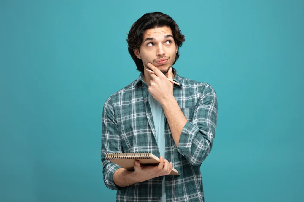 Sessão, seção ou cessão? Diferença, dicas e questões 1 rapaz com dúvida enquanto escreve representa sessão, seção ou cessão