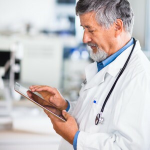 Senior doctor using his tablet computer at work