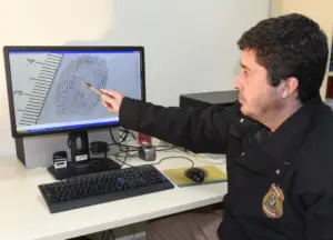 Foto de um Auxiliar de Papiloscopista coletando impressões digitais s