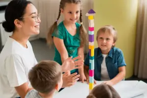 Imagem de um auxiliar escolar acompanhando crianças em uma atividade lúdica na sala de aula.