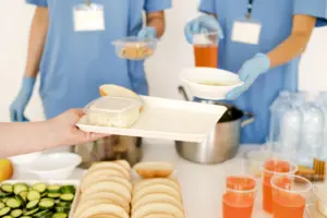 Atendente de Nutricionista em ação, montando bandejas e distribuindo refeições