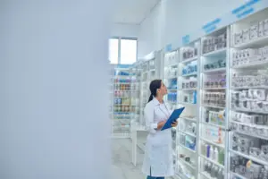 Foto de um assistente de farmacia organizando prateleiras em uma farmácia hospitalar.