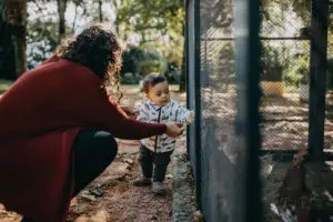 Moça auxiliando criança em área externa. cuidador social