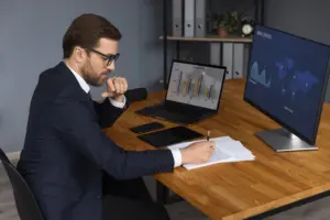 Auditor de Tributos analisando documentos fiscais, com calculadora e gráficos, representando o trabalho de auditoria.