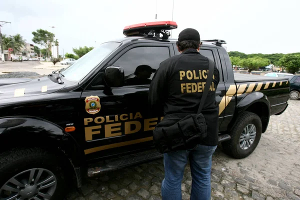 policial federal de costas entrando em viatura escrito policia federal no uniforme