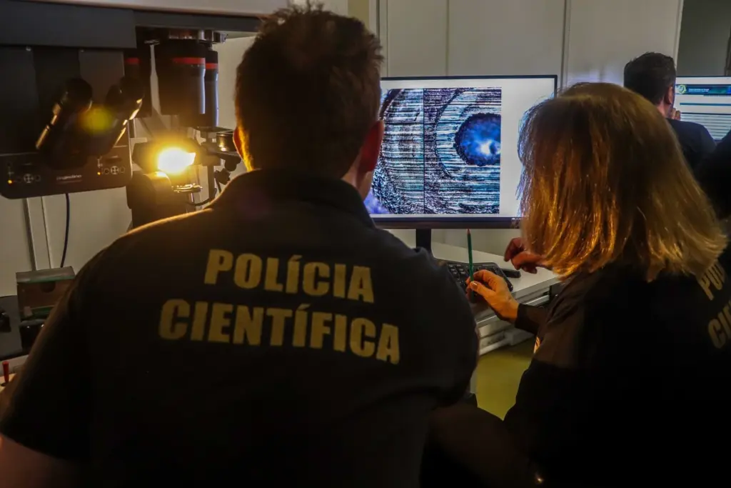 dois policiais científicos de costas fazendo uma investigação no computador