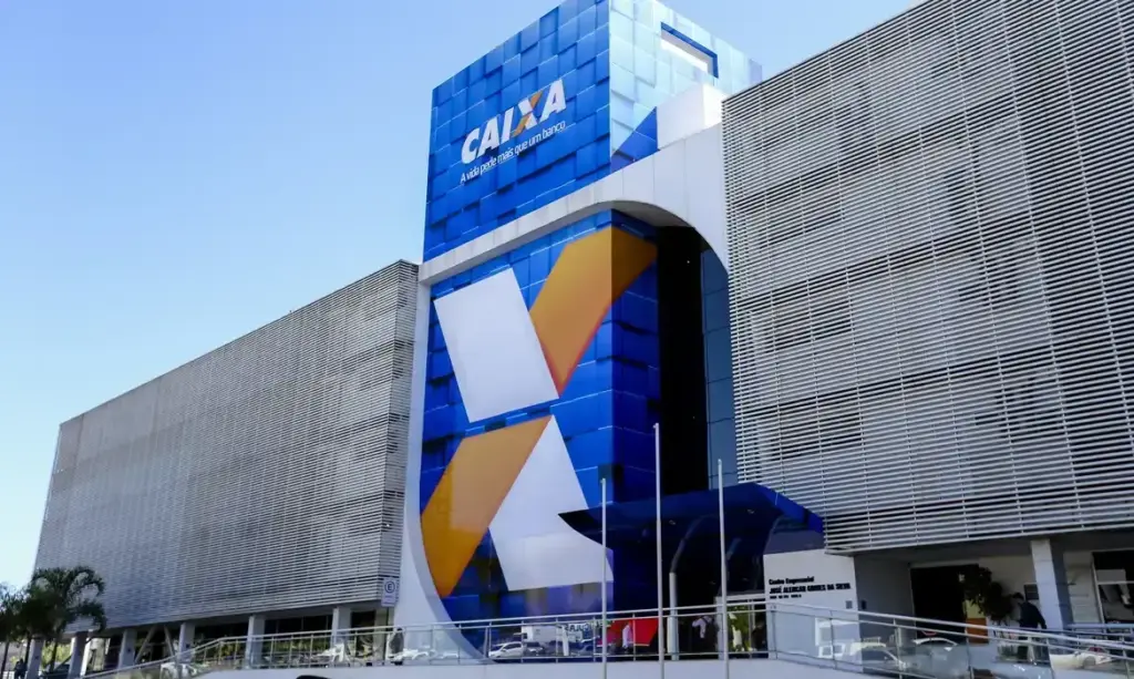 predio da caixa econômica federal com a fachada azul, laranja e branco. Ao meio a logo da caixa com a letra x. 