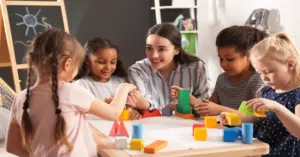 Alunos em sala de aula com professora ao fundo durante atividade / Concurso SME SP