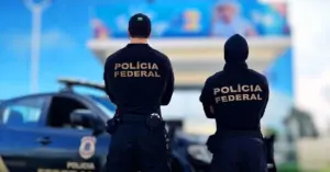 Dois policiais federais de costas em frente a viatura / Edital PF Policial