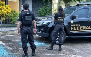 Policiais Federais ao lado do carro do concurso pf