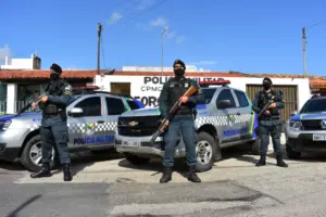 Policiais Militares armados ao lado do camburão do concurso pm se